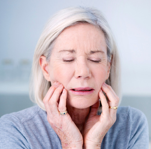 Woman in light blue shirt with discomfort from failed dental implant