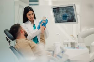 dentist showing a male patient a mouth mold